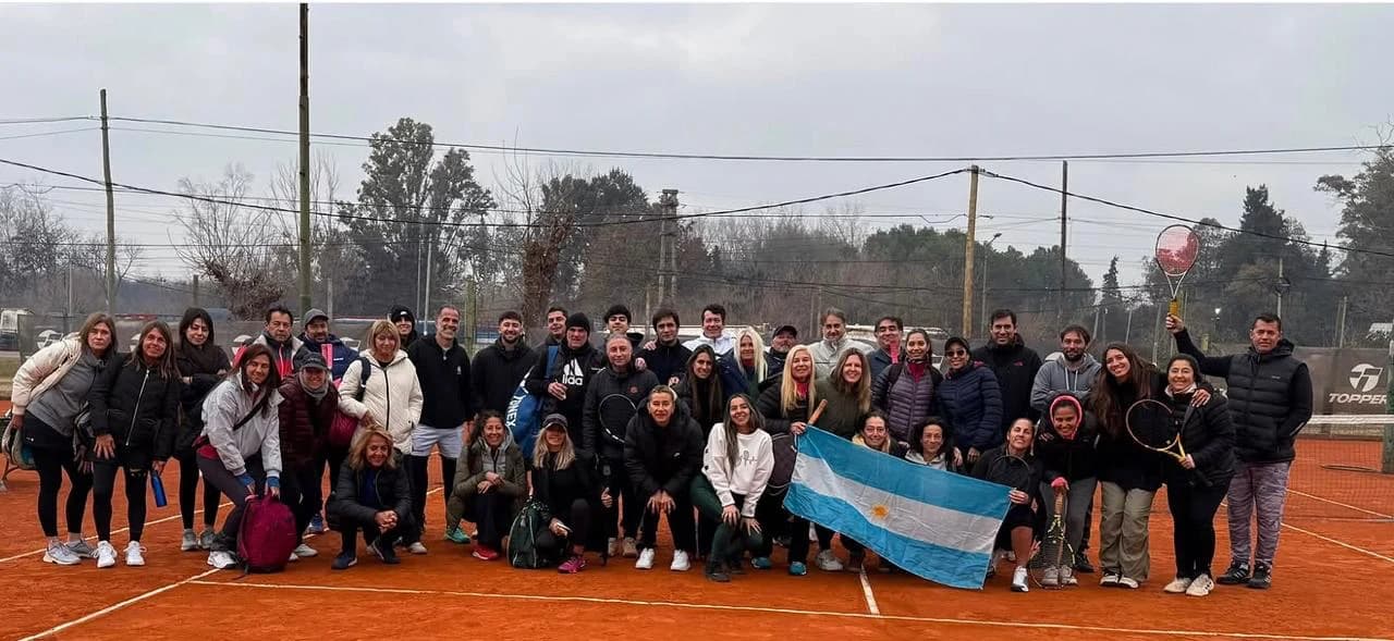 Grupo de jugadores de tenis reunidos sobre una cancha de polvo de ladrillo